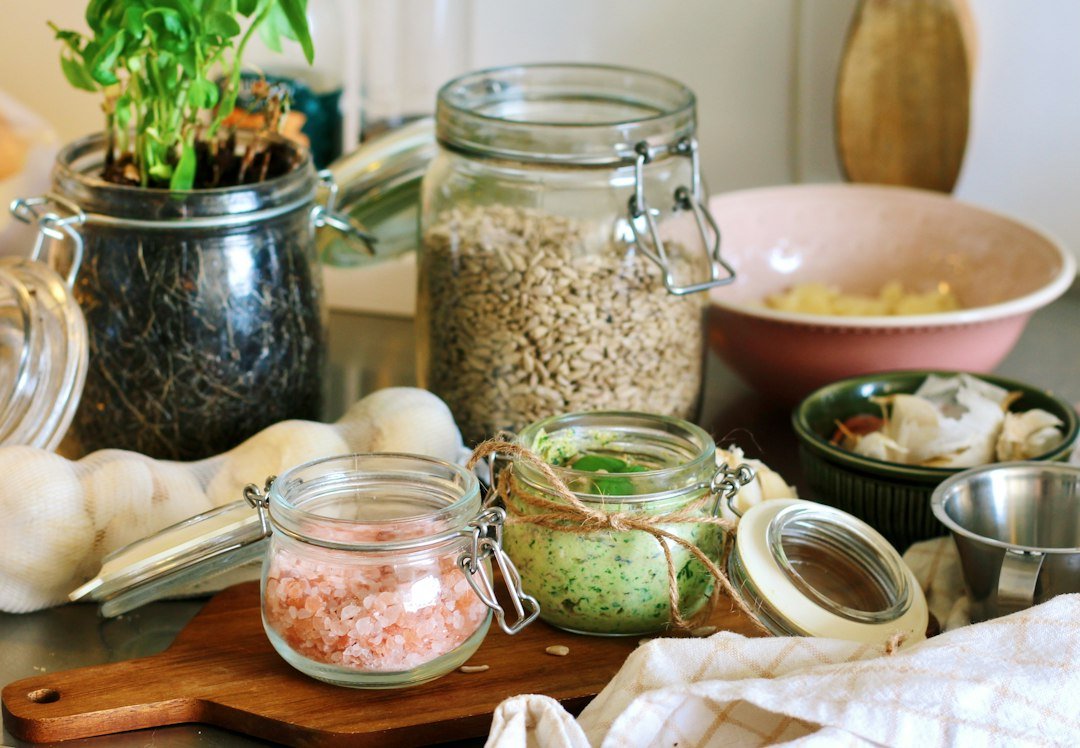 A glass jar of homemade green sauce with fresh ingredients.